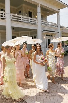 a group of women standing next to each other holding umbrellas in front of a building