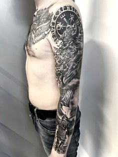 a man with a clock tattoo on his arm and shoulder, standing in front of a wall