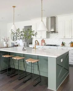 a kitchen island with three stools next to it