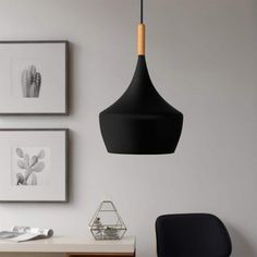 a black lamp hanging from a ceiling in a room with pictures on the wall above it