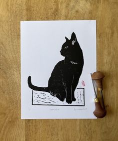 a black cat sitting on top of a wooden table next to a pair of scissors