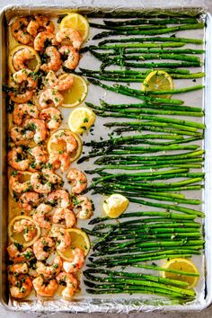 asparagus, lemons and shrimp on a baking sheet