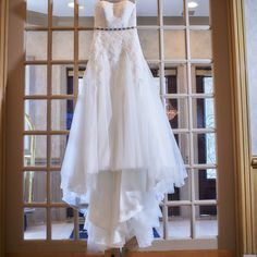 a wedding dress hanging in front of a window