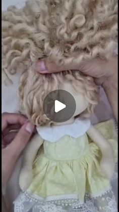 a doll being held up by someone's hands with curly hair on top of it