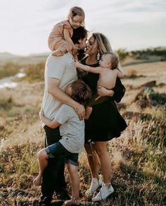 a group of people standing around each other in a field with one woman holding a baby