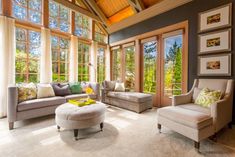 a living room filled with furniture and windows covered in wooden beams, along with white carpeted flooring