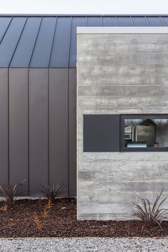 the side of a building with a small window on it's side and plants next to it