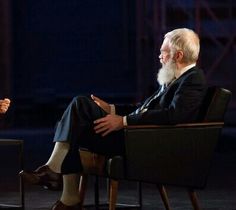 two men sitting in chairs talking to each other