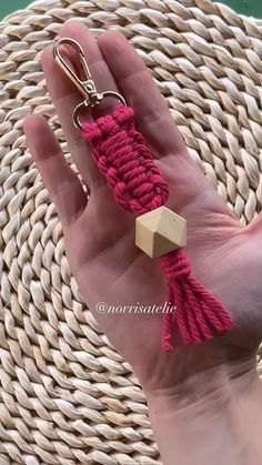 a hand holding a keychain that has a wooden block on it with a tassel