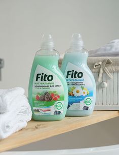 two bottles of fitto sitting on top of a wooden shelf next to towels and a basket