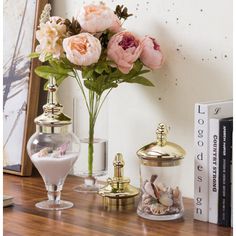 flowers are in vases on a table next to books and other items that include seashells