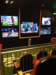 an empty sports stadium with three televisions on the wall and seats in front of them