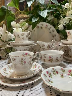 a table topped with lots of white dishes and cups