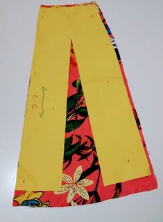 a yellow and pink skirt with flowers on it sitting on top of a white table