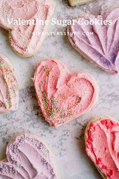 heart shaped sugar cookies with pink frosting and sprinkles on a marble surface