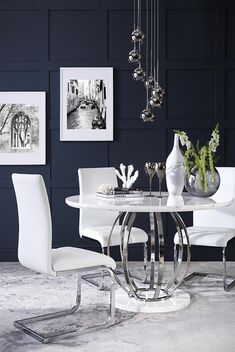 a white table and chairs in a room with pictures on the wall behind it,