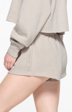 Keep your look laid-back and luxe in casual sweat shorts made from supersoft cotton-blend fleece in a relaxed fit brought to you by Kim Kardashian's SKIMS. 3" inseam; 28" leg opening; 10 1/2" front rise; 16" back rise (size Medium) Elastic waist 70% cotton, 30% polyester Machine wash, tumble dry Imported Solid Color Comfort Waistband Shorts For Loungewear, Comfy Solid Color Loungewear Shorts, Relaxed Cotton Shorts For Lounging, Relaxed Solid Shorts For Leisure, High-waisted Shorts With Ribbed Waistband For Loungewear, Solid Color Cotton Pajama Shorts For Lounging, Cozy Cotton Shorts, Comfy Bottoms With Built-in Shorts For Spring, Loungewear Shorts With Comfort Waistband