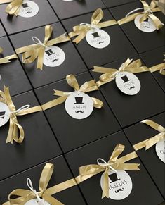 many different types of tags tied together with gold ribbons and bows on black tiles,