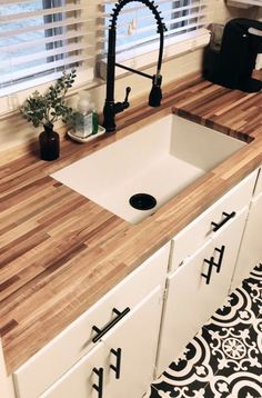 a kitchen sink sitting under a faucet next to a window