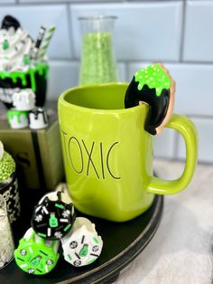 a green coffee cup with black and white candies in it next to other candy