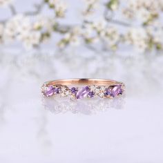 an image of a wedding ring with purple stones on the side and white flowers in the background