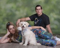 a man and woman sitting on the floor with their dog