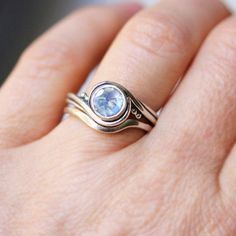 a woman's hand holding a ring with a blue topazte on it