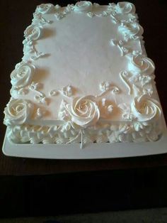 a square cake with white frosting roses on it