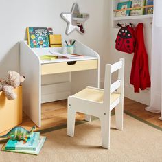 a child's desk and chair in a room with books on the floor, toys nearby