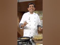 a man in a chef's uniform is cooking food on a stove top and smiling at the camera