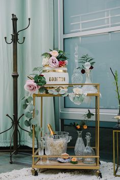 a gold bar cart with flowers and champagne glasses on the top, along with other items