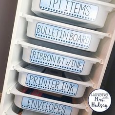 four plastic containers with labels on them are stacked up in a storage unit for organizing