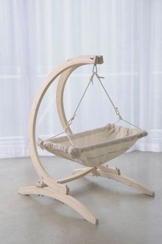 a wooden swing with a baby in it on top of a white floor next to a window