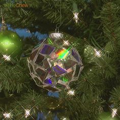 an ornament hanging from a christmas tree in front of some green and silver ornaments