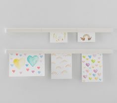 several cards hanging on a wall with hearts and rainbows