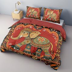 a bed with an elephant on it and red comforter set in front of a night stand