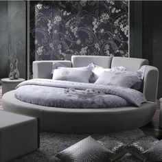 a round bed sitting on top of a wooden floor next to a wall covered in black and white flowers