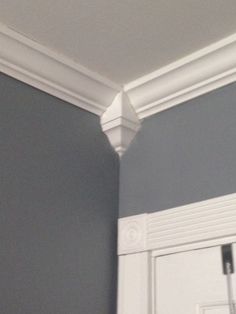 the corner of a room with gray walls and white molding on the trimming