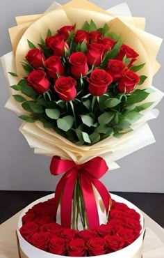 a large bouquet of red roses in a round white box with a ribbon around it