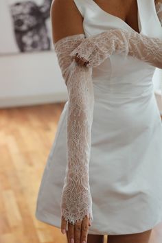 a woman in white dress holding on to her arm with lace overlaying it