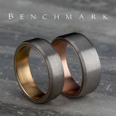 two gold and silver wedding bands with the words ben chmark on it's side