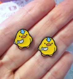 two yellow rubber ducks sitting on top of a persons hand in front of a piece of paper