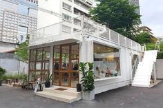 a white building with stairs leading up to it's second floor and people standing in the doorway