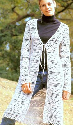 a woman standing on top of a rock wearing a white cardigan sweater and black pants