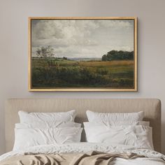 a painting hanging above a bed in a room with white linens and pillows on it