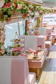 the interior of a fancy restaurant with pink and white booths, flowers on the wall