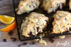 some scones are cooling on a wire rack with orange slices and chocolate chips next to them