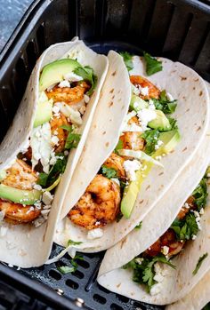 three shrimp tacos with avocado and cilantro