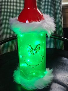 a green plastic bottle with a grin face on it's side and a santa hat on top