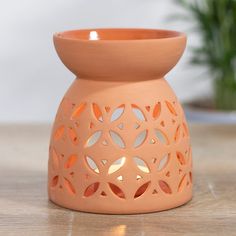 an orange vase sitting on top of a wooden table next to a potted plant